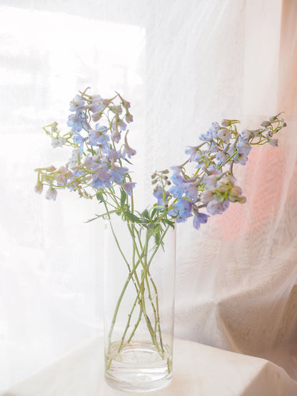 Clear glass vase with a delicate light violet flower by La Rose Fleur, a touch of understated elegance.